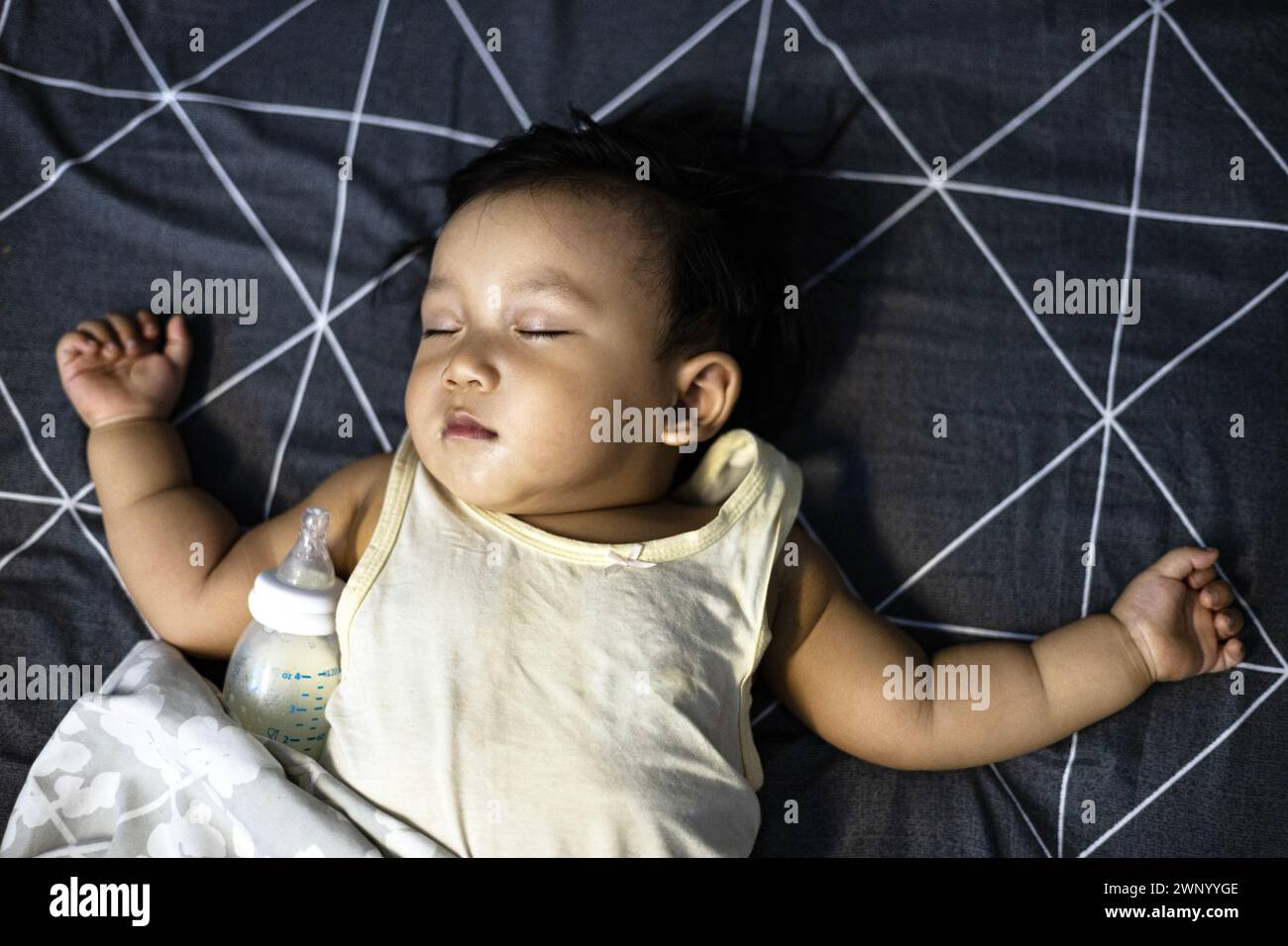 Baby sleeping on a bed after drinking bottle milk. baby boy sleeping with bottle with formula milk. Stock Photo