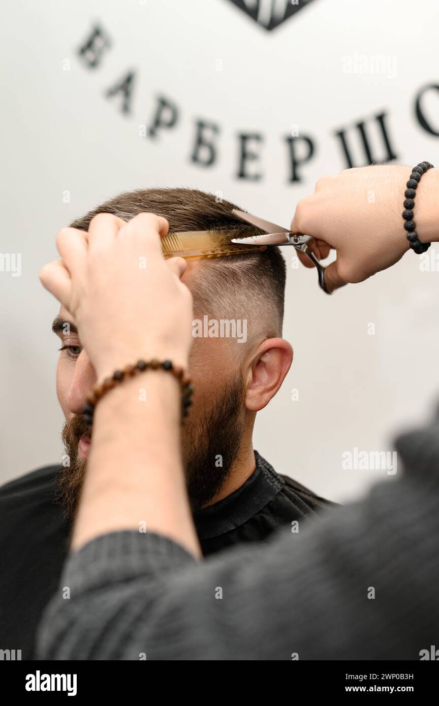 Haircut and alignment of the contour of the head with scissors. Short ...