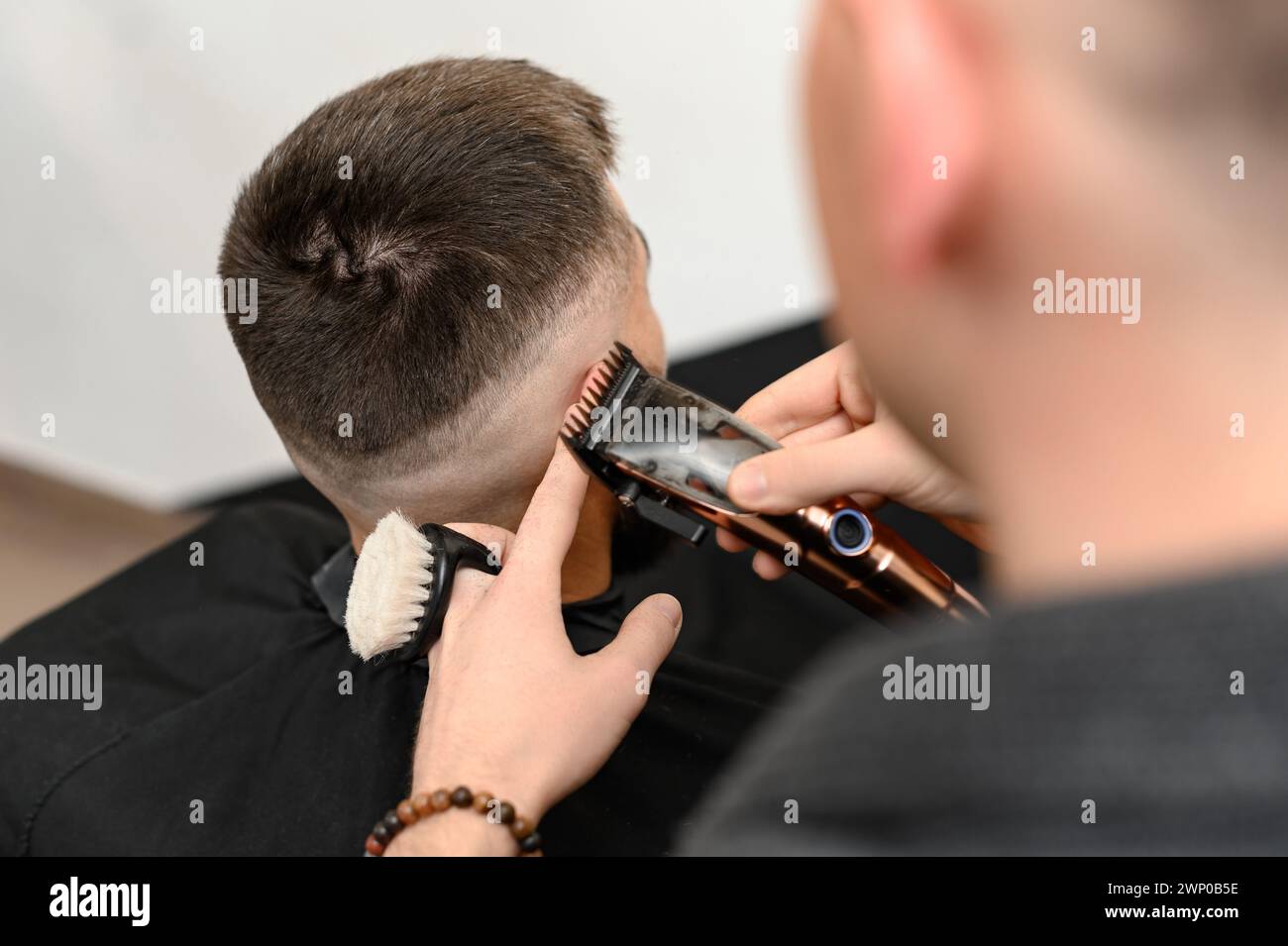 Haircut and alignment of the head contour with a hair clipper and trimmer. Short haircut in the barbershop. Stock Photo