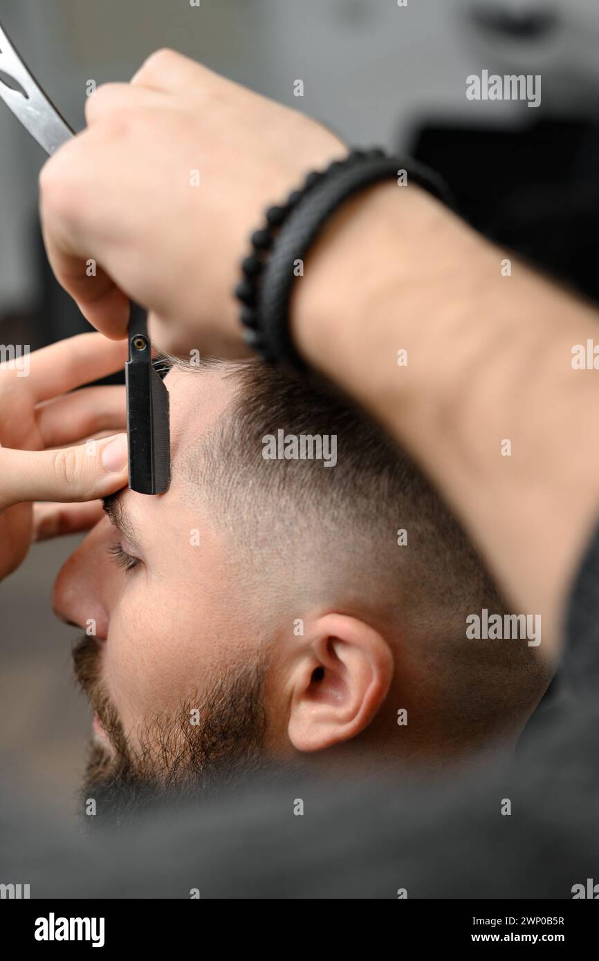 The barber makes the outline with a dangerous razor during the undercut haircut Stock Photo
