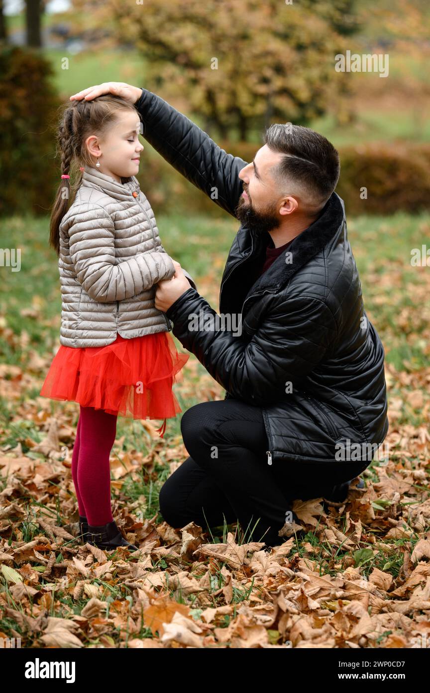 Portrait of dad with daughter in autumn park with yellow leaves, parenthood. Stock Photo