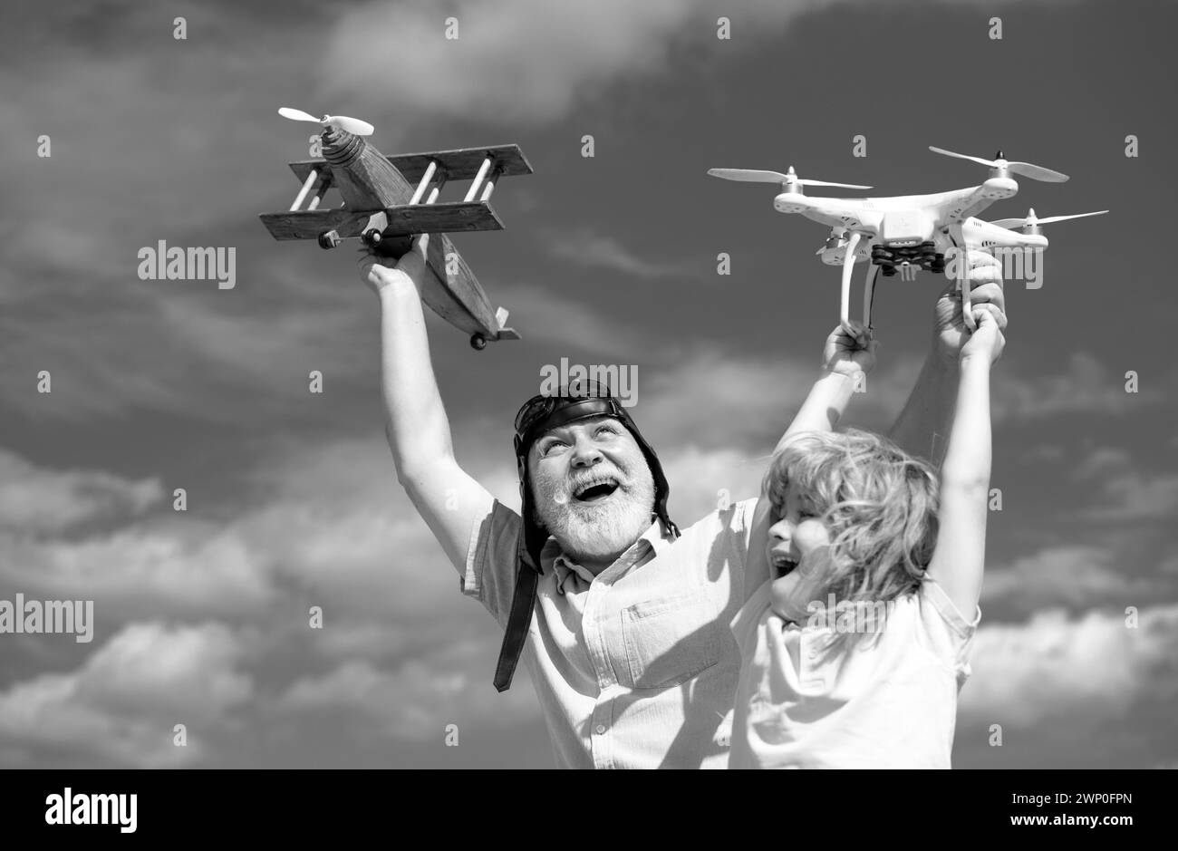 Excited grandson child and funny amazed grandfather with plane and