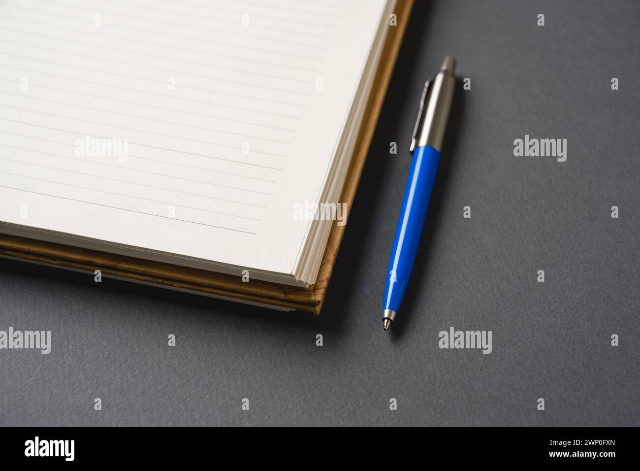 Ballpoint pen made of blue plastic and metal standing on lined notebook Stock Photo