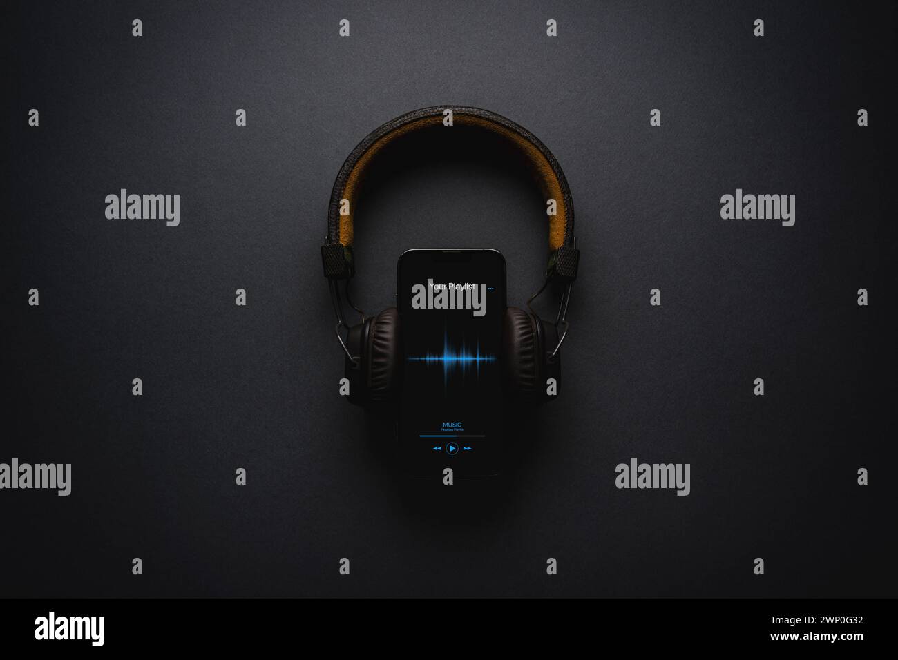 Smartphone with music player app and on-ear headphones on dark gray background Stock Photo
