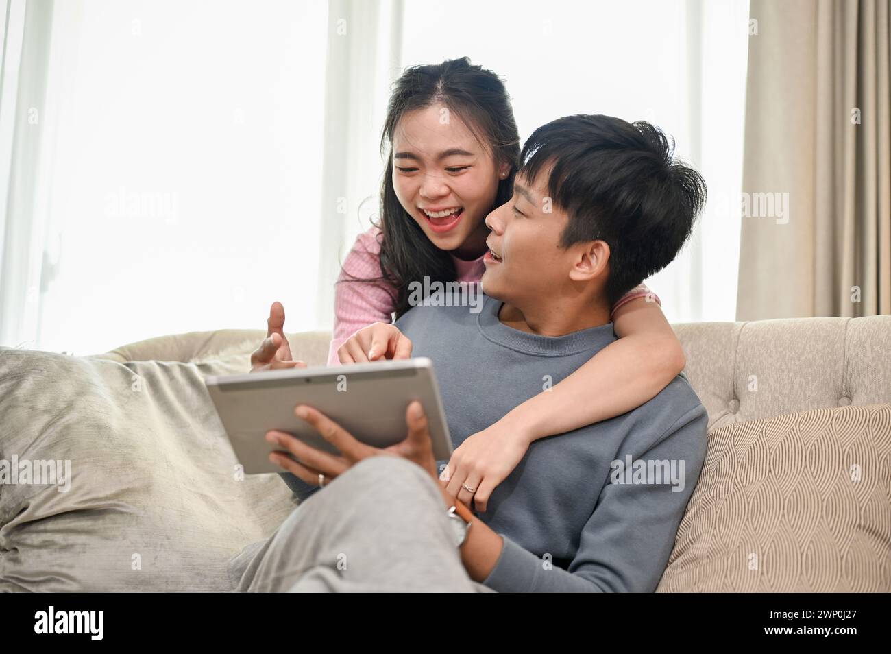 A smiling, happy Asian woman is hugging her boyfriend or fiancé from ...