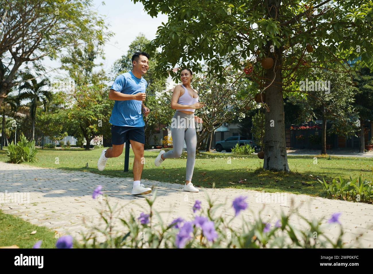 Positive diverse couple jogging in park to stay fit Stock Photo