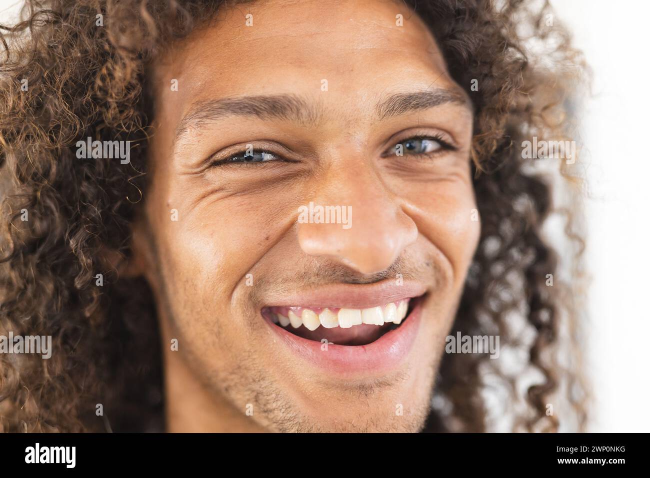 Young biracial man with curly hair smiles brightly Stock Photo