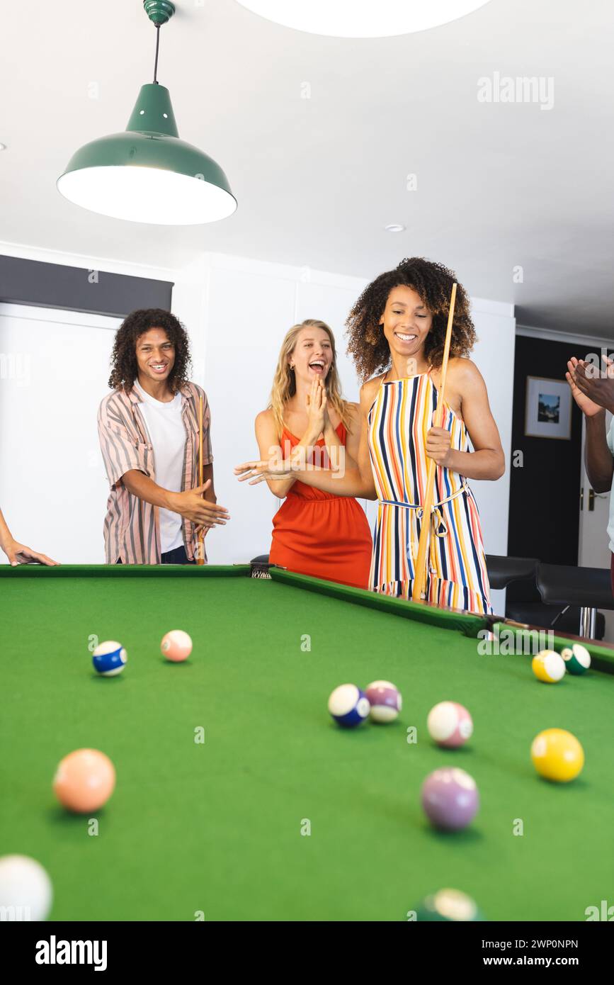 Young biracial man and two young Caucasian women enjoy a game of pool Stock Photo