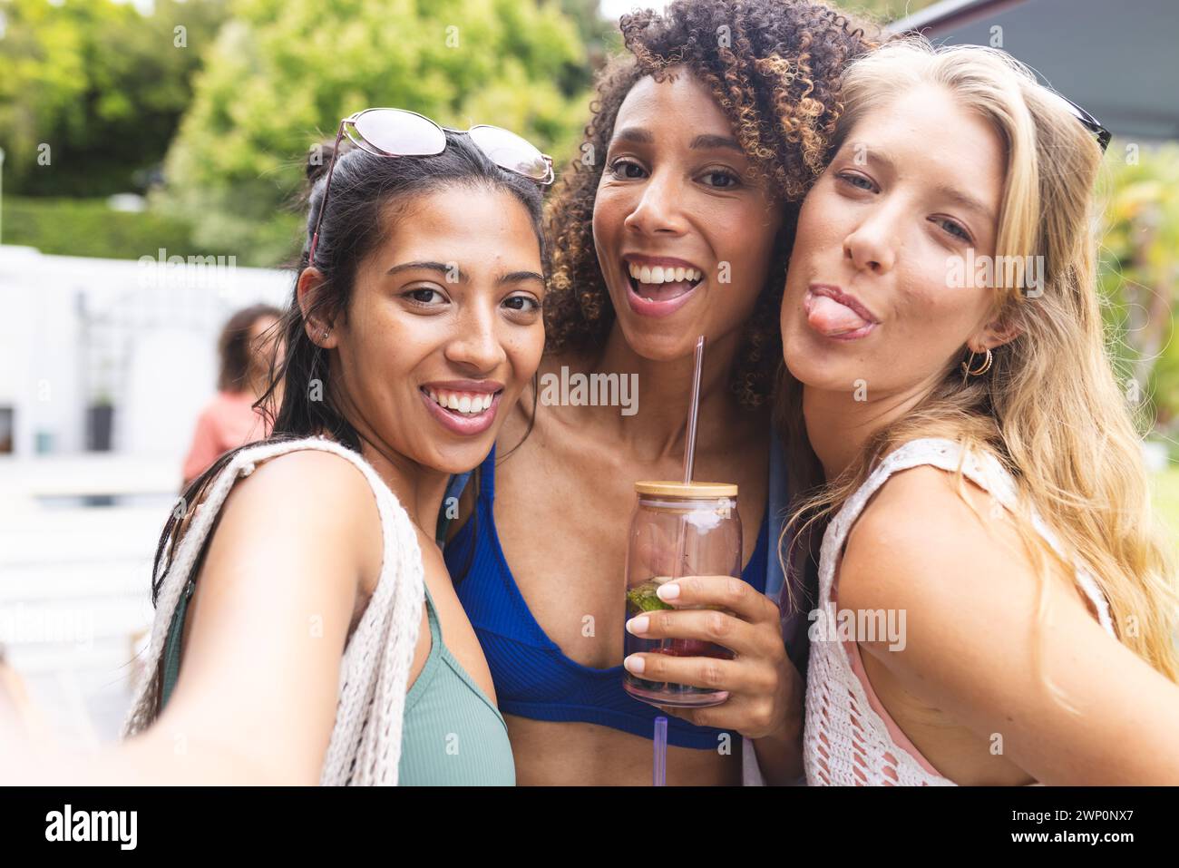 Three young women pose playfully, one sticking out her tongue Stock Photo