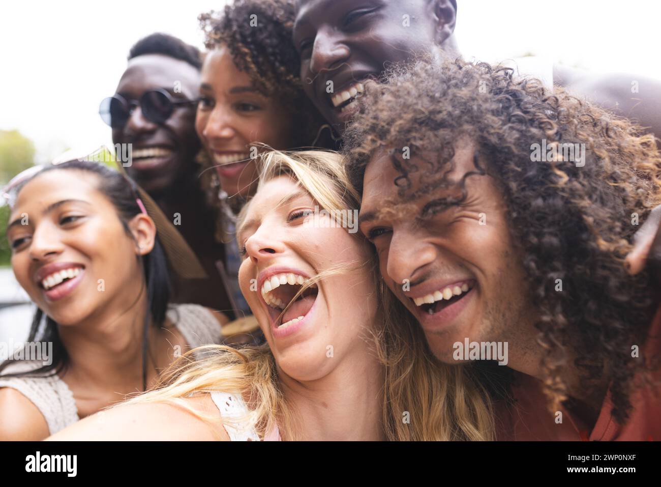 Diverse group of friends share a joyful moment, laughing together outdoors Stock Photo