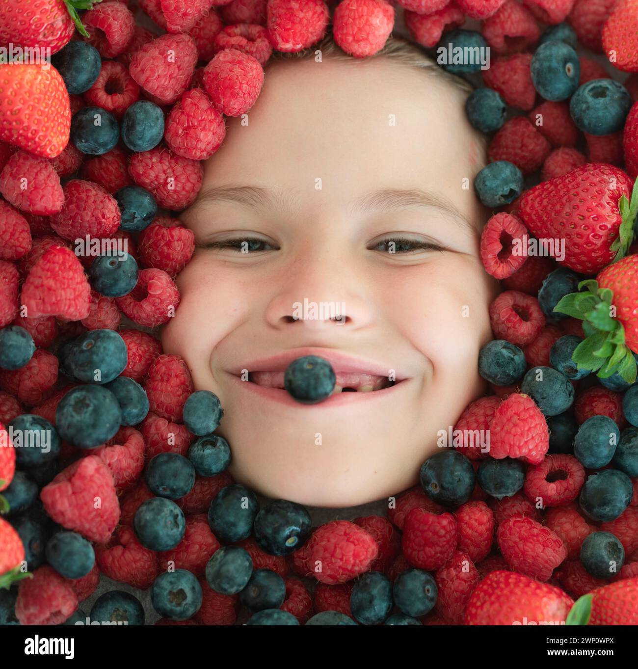 Berries child face close up. Top view photo of child face with berri
