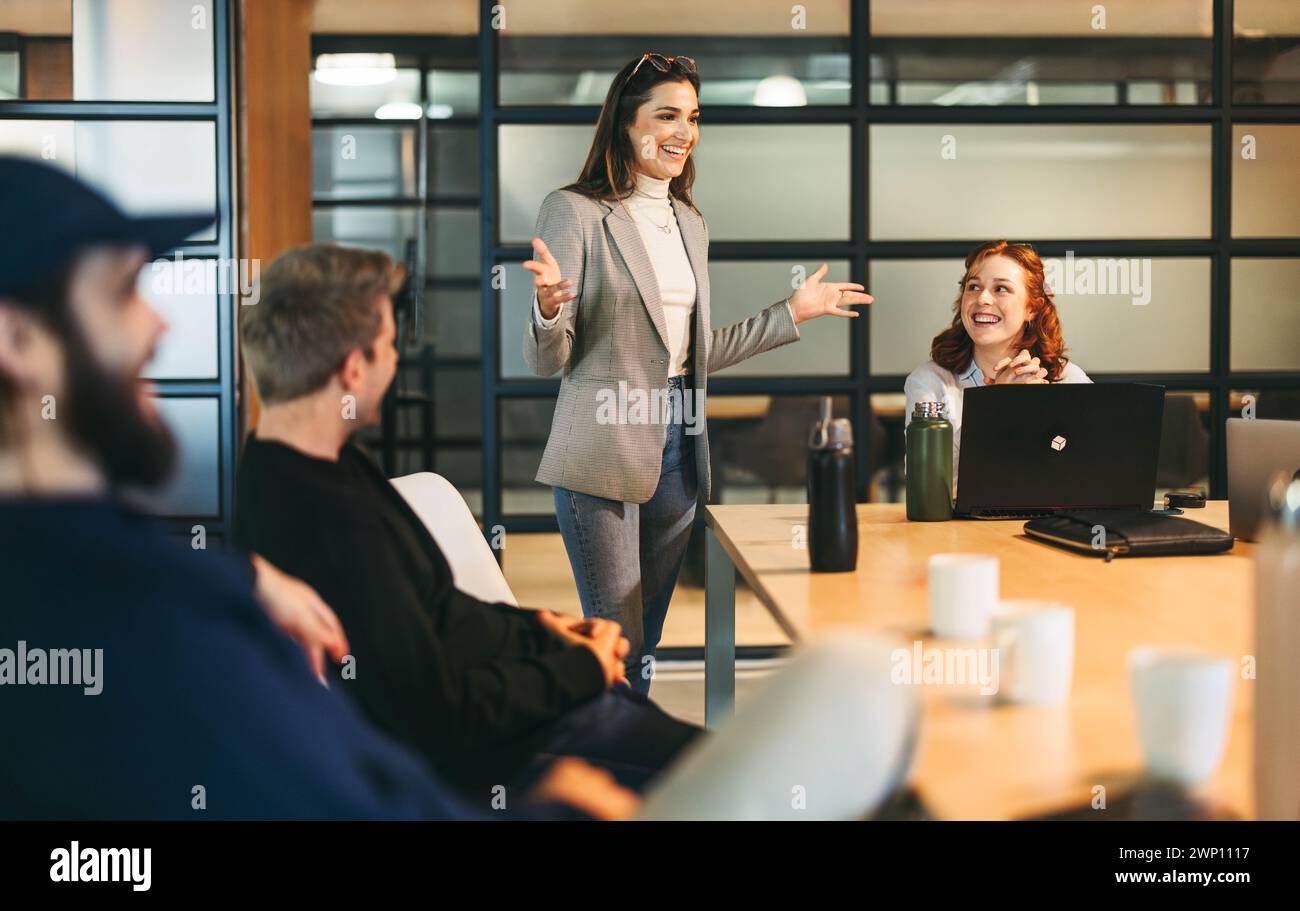 Diverse professionals, both men and women, brainstorming and discussing ideas in a lively office meeting. Led by a charismatic leader, this successful Stock Photo