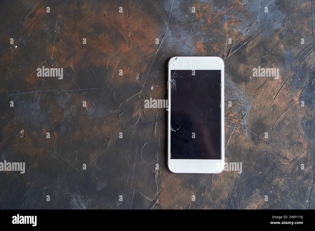 White phone with a broken screen on dark background Stock Photo
