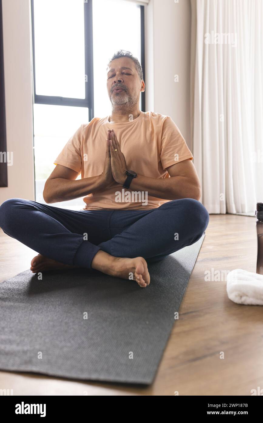 Biracial senior man meditates with hands in prayer position, eyes closed Stock Photo