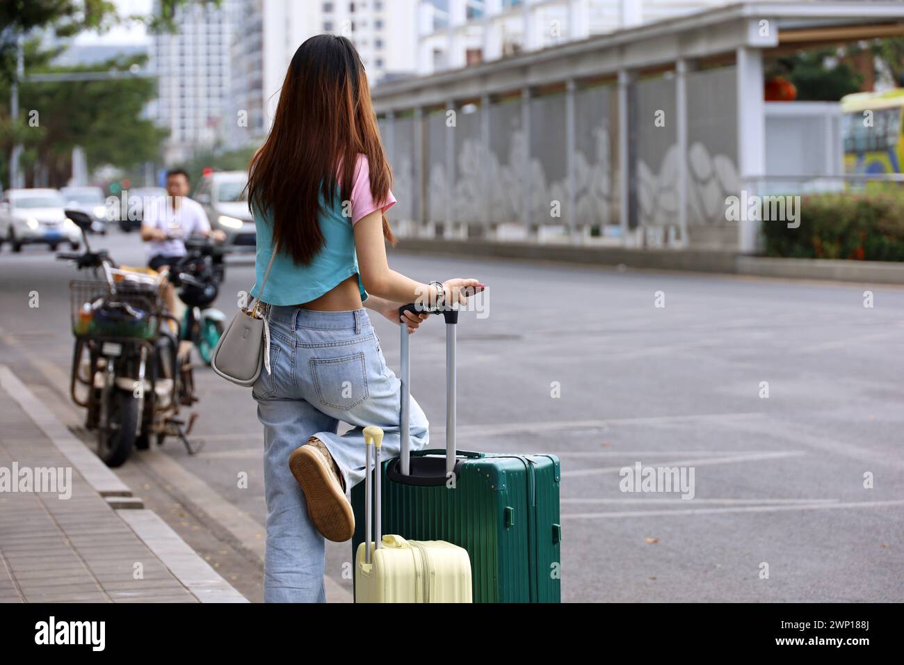 Girl in jeans standing with a suitcases on city street. Concept of travel and summer holidays Stock Photo