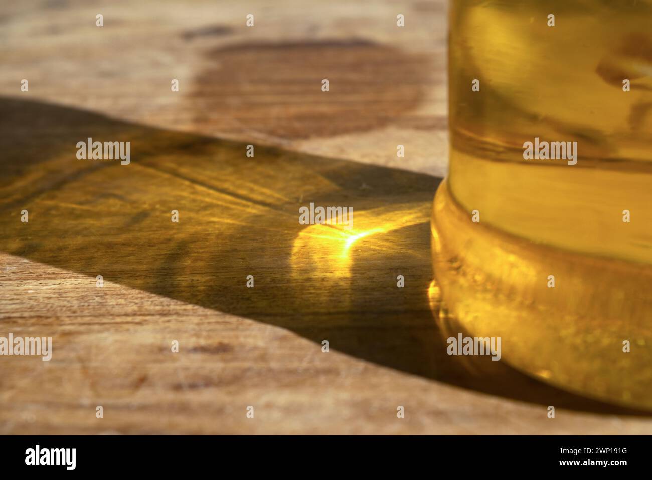 Oil Rings Reflection sun reflection through a bottle of olive oil in glass on a wooden ...