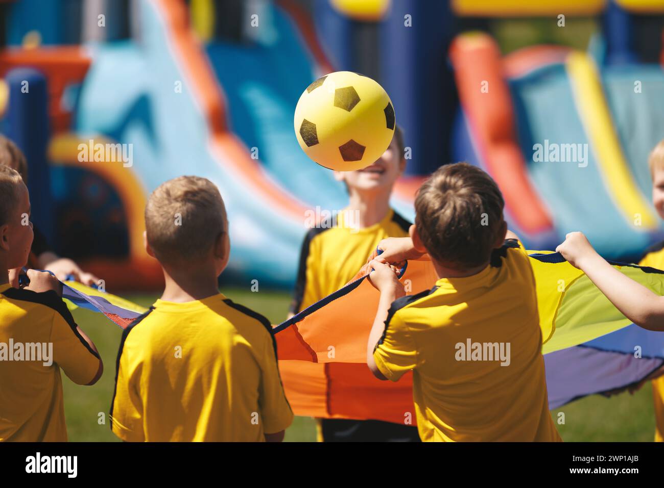 Happy kids playing at festival. School boys having fun and bouncing soccer ball together. Colourful toys for children Stock Photo