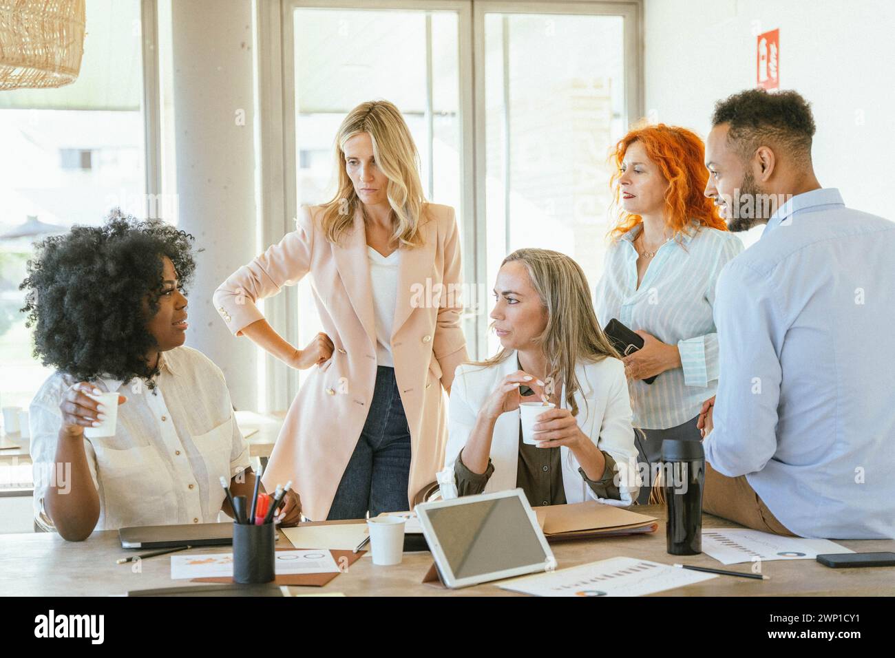 Team of coworkers gathering in the office while talking about a new project. Business concept. Stock Photo