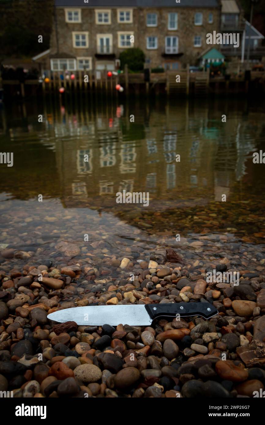 Knife on the beach with village in background Stock Photo