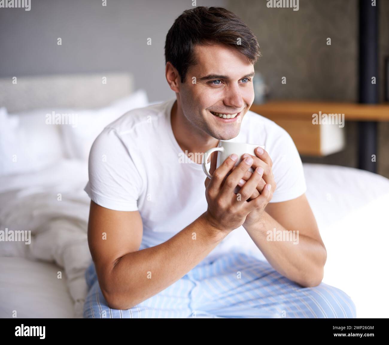 Man, bedroom and morning coffee sitting and thinking, weekend off in apartment to relax with attractive male person. Casual and holiday or home Stock Photo
