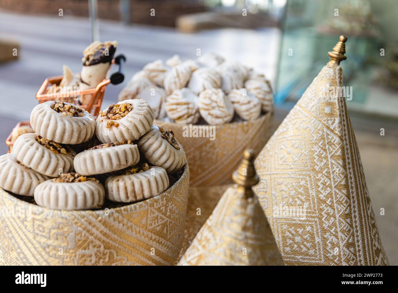 Horizontal photo a selective focus shot captures the intricate detail of artisanal Arabic pastries arrayed on a stand wrapped in traditional patterned Stock Photo