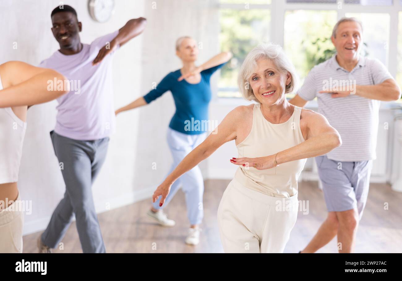 Elderly woman practicing vigorous dance during group class Stock Photo