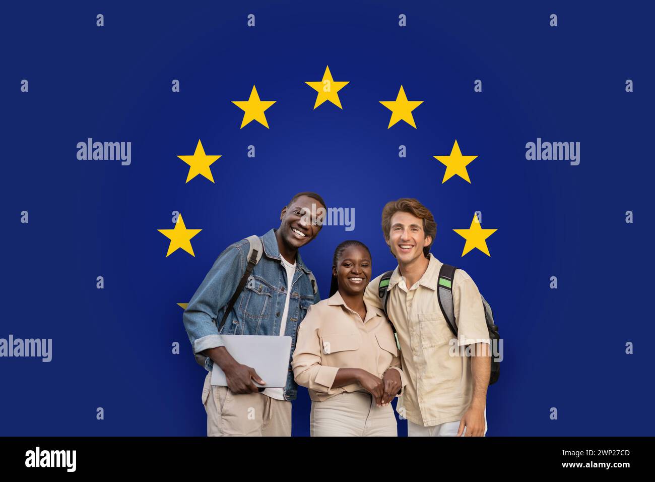 Three smiling students with backpacks and a laptop standing together Stock Photo
