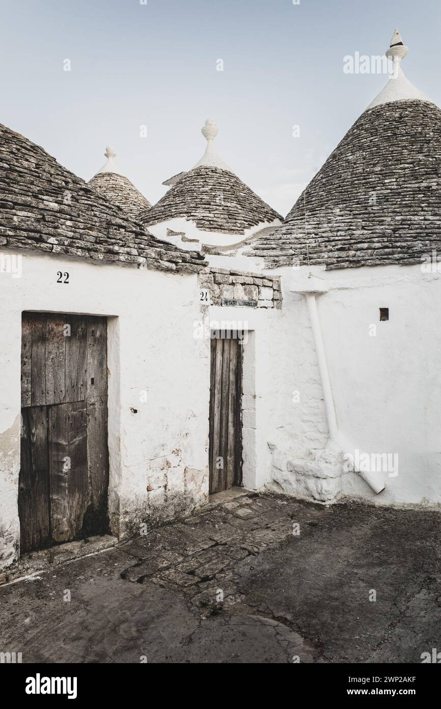 ITALY, PUGLIA, ALBEROBELLO: Street views of the trulli of Alberobello at sunset. The city of Alberobello is famously known as the capital of the trulli, the characteristic stone buildings with a conical roof that never like others, represent in the imagination, the entire Puglia region. It was born as a basic building for agricultural needs, the trulli were in fact used as temporary shelters, deposits, stables, and as the technique was refined, as homes. Stock Photo