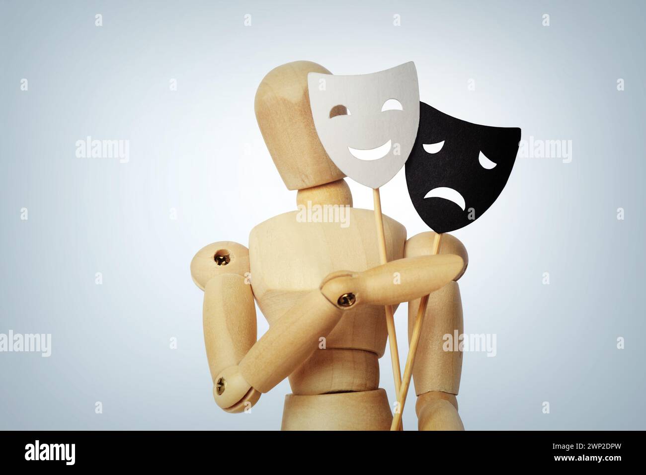 Wooden mannequin with two masks showing different emotions - Concept of psychology, mood change and bipolar disorder Stock Photo