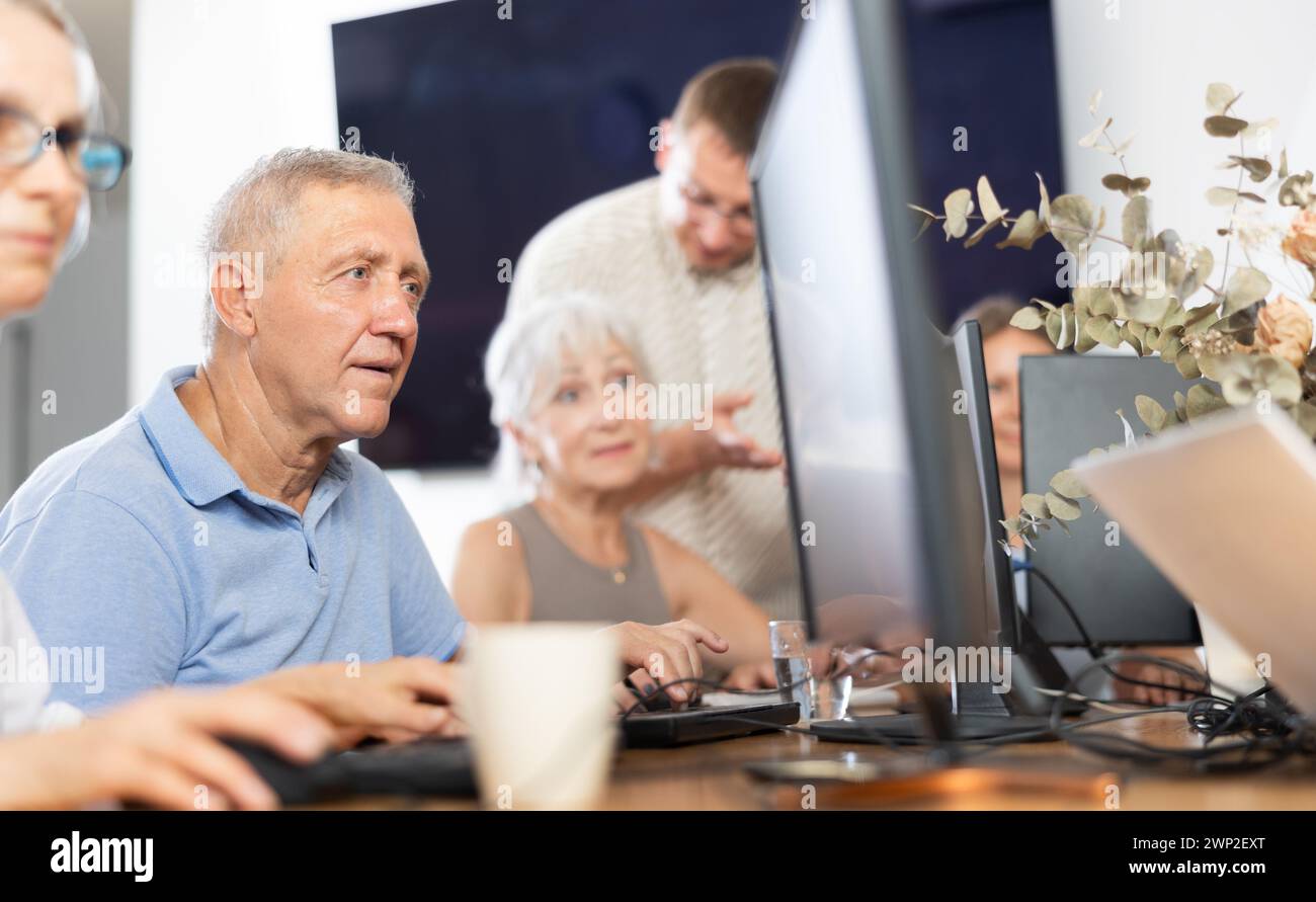 Focused older gentleman using computer at internet cafe Stock Photo