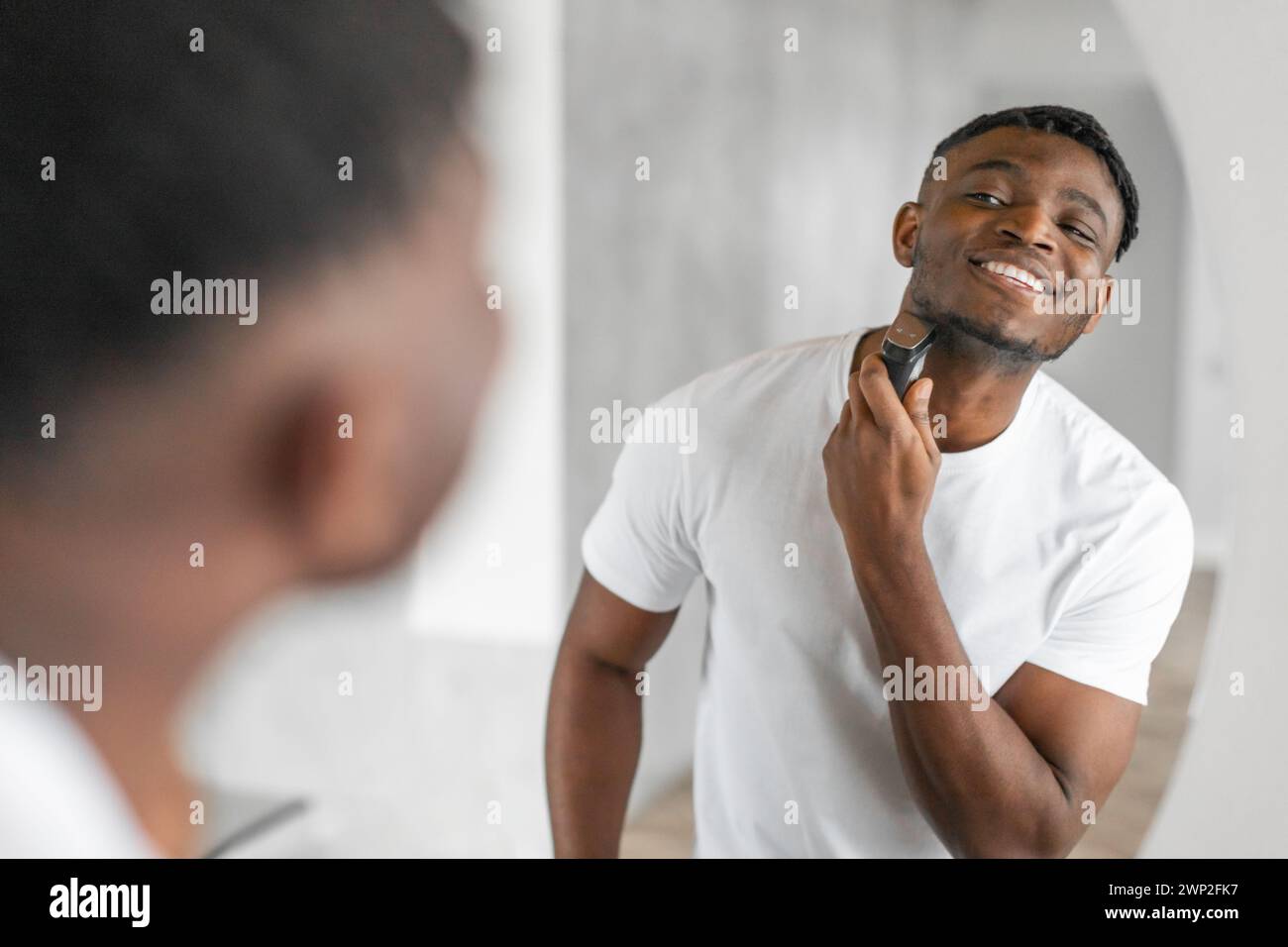 Happy African American man shaving with an electric razor indoor Stock ...