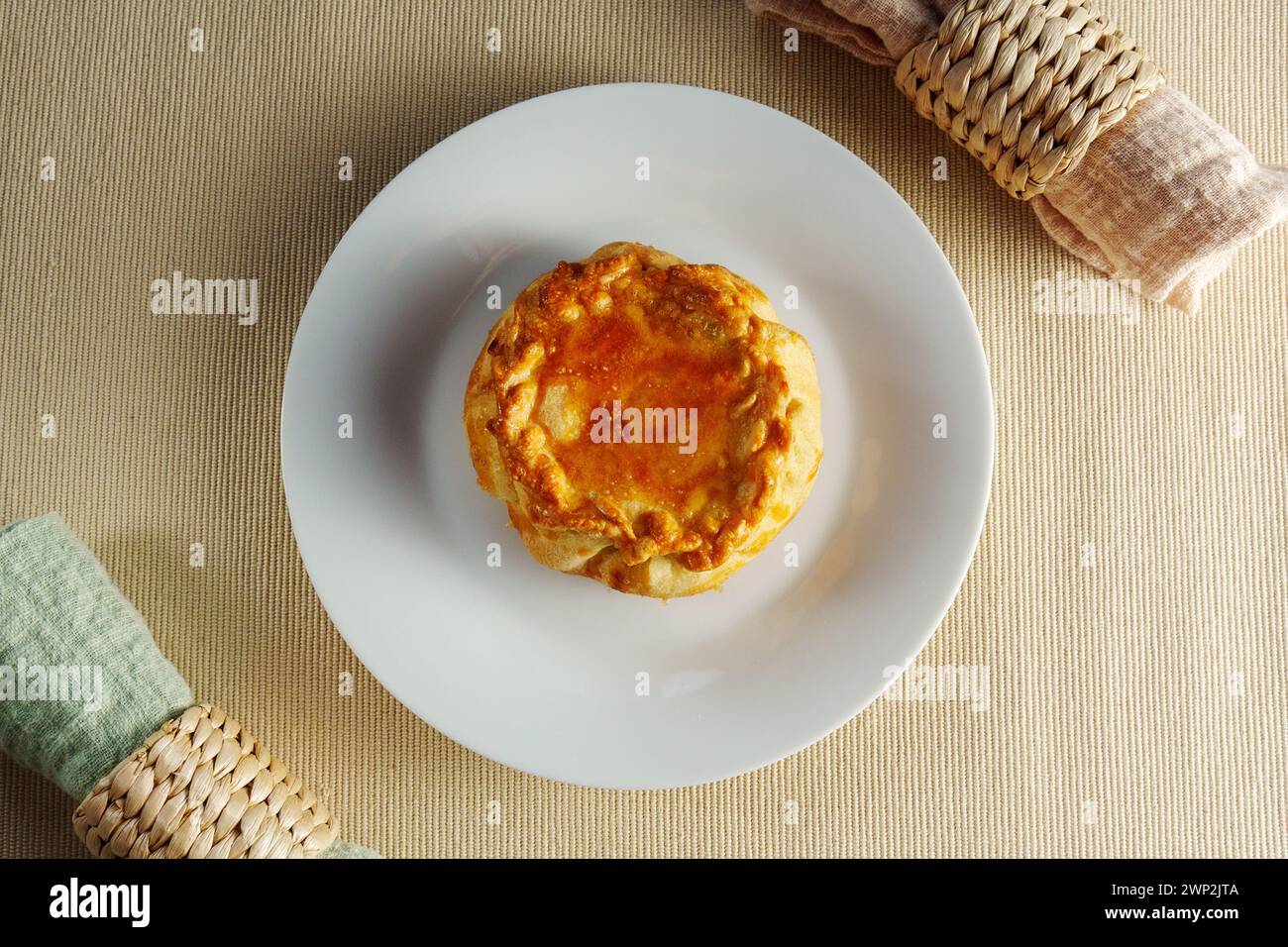 A Flaky Delight: A White Plate Showcasing a Delectable Pastry on a Mesmerizing Table Stock Photo