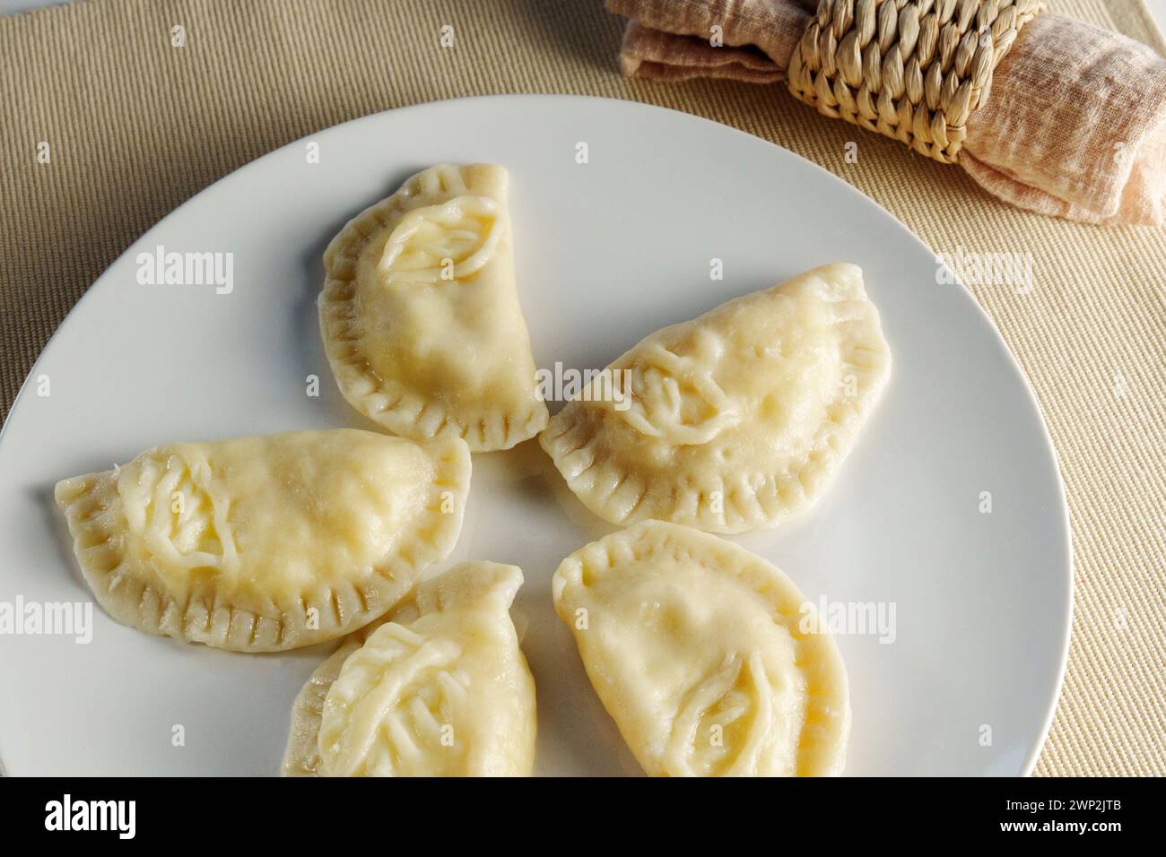 Elegance of perfectly crimped crescent dumplings, or ravioli, presented on a white plate, ready to entice any food connoisseur. Stock Photo