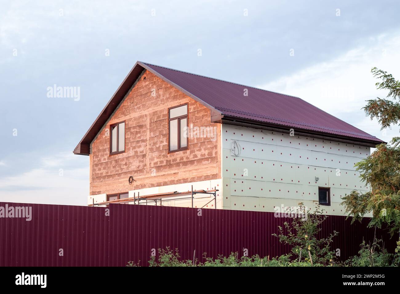 A two-story house under construction with a corrugated roof in the ...