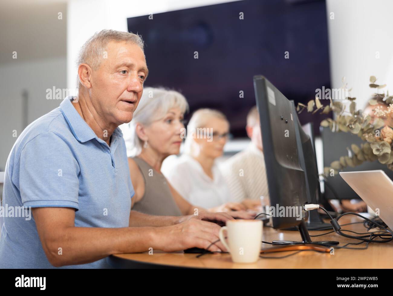 Old man learning computer programs in training room Stock Photo