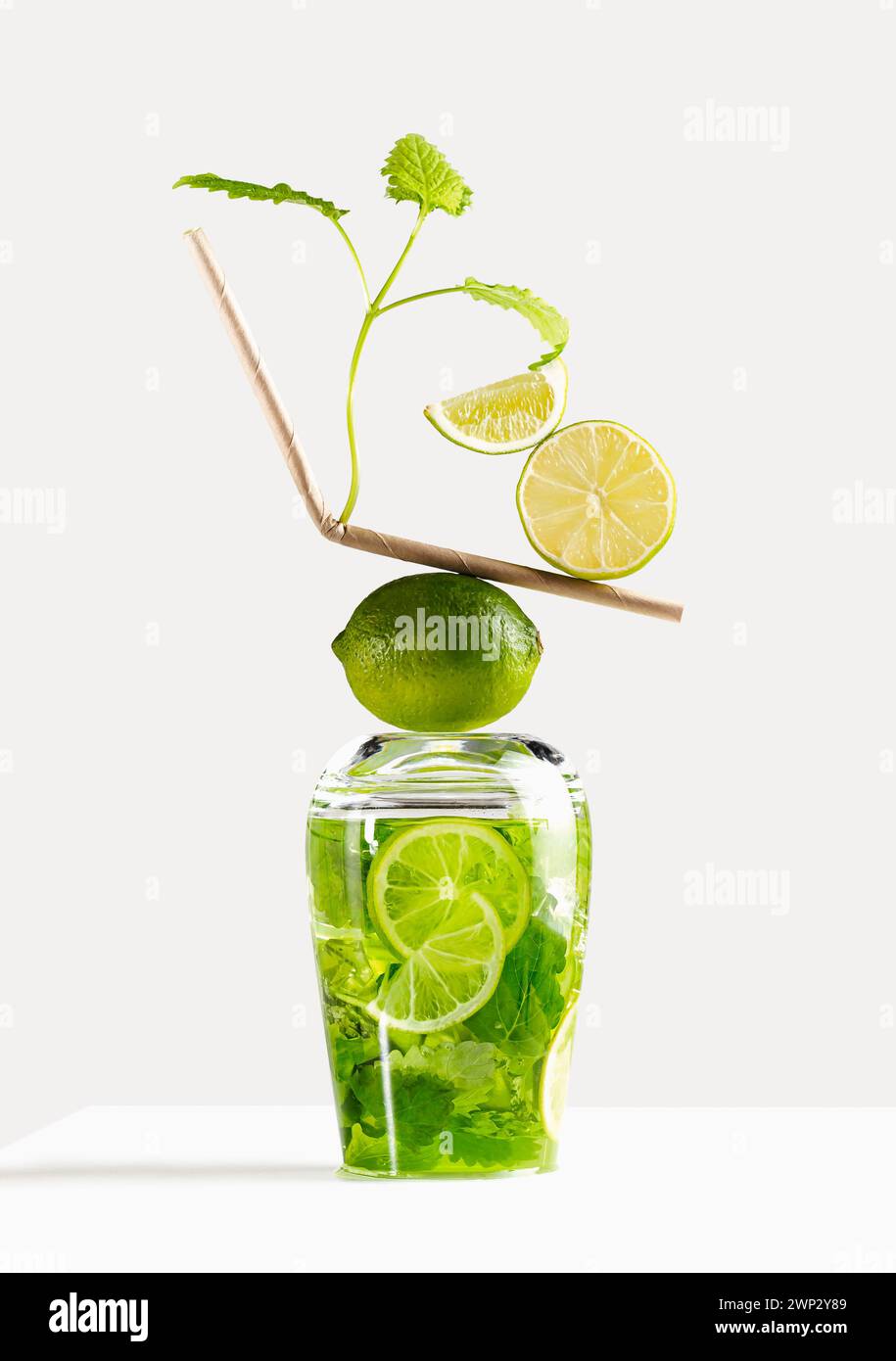 Balance - mojito cocktail in an inverted glass on a light background with a paper tube, limes and mint. One of set mojito Stock Photo