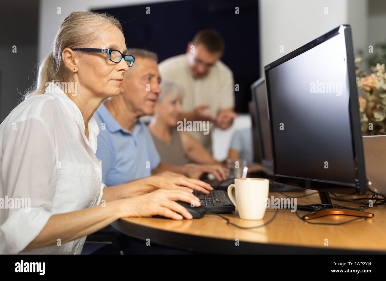 Old woman learning computer programs in training room Stock Photo