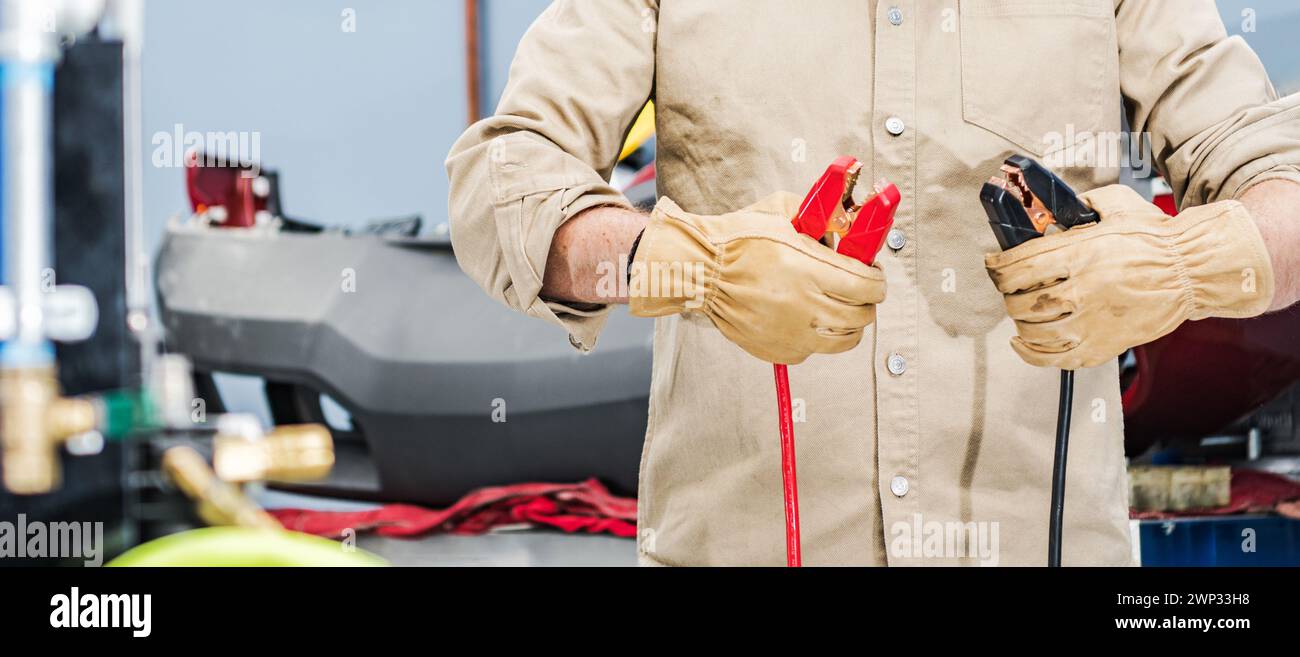 Professional Vehicles Mechanic with a Car Jumping Cables in His Hands Stock Photo