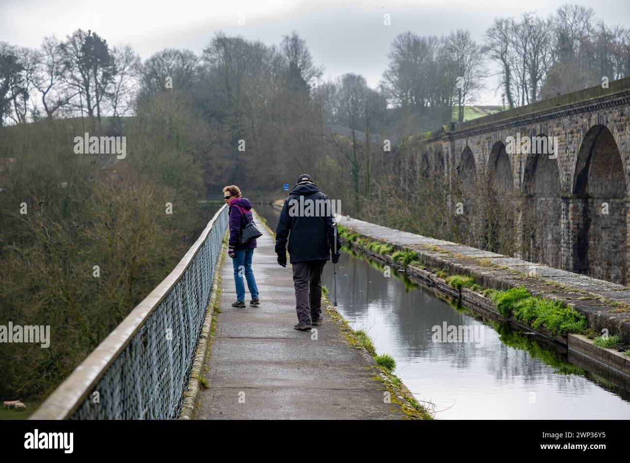 An older couple walking on the towpath beside the  Llangollen Canal as it flows across the Chirck Aqueduct on the English Welsh border. Stock Photo