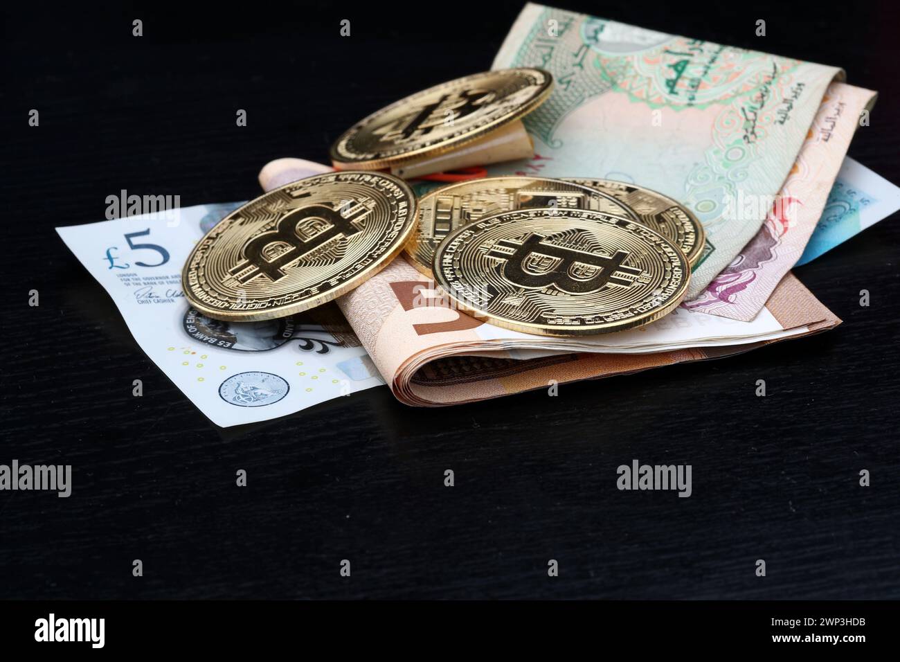 Symbolbild:  diverse Bitcoins auf Geldscheinen: Pfund, Euro und Dirham - die Alternative für Weltwährungen? - Der Bitcoin steht hoch im Kurs. Selbst F Stock Photo