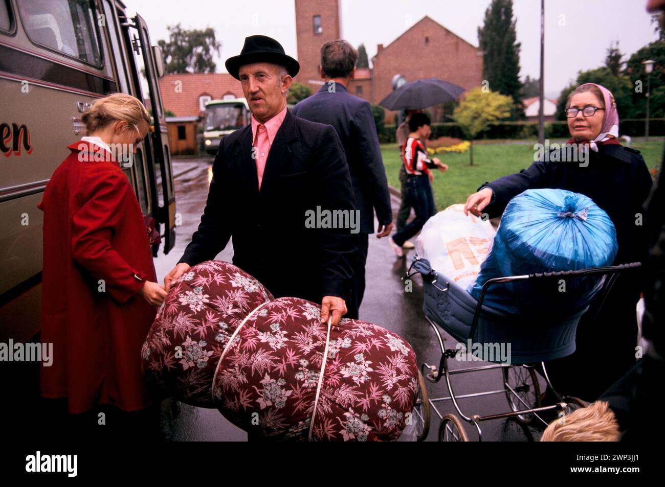 Friedland, Gottingen, Lower Saxony, Germany 1985. Friedland refugee camp, Russian Soviet-Germans return as refuges from the Soviet Union to freedom. This group of refugees leave the transit welcome camp with their belongings for a journey to a new life. During Perestroika in the 1980s, the Soviet borders were temporarily opened and the beginnings of a massive migration of Germans from the Soviet Union occurred. Entire families, and even villages, would leave their homes and relocate together in Germany or Austria. HOMER SYKES Stock Photo