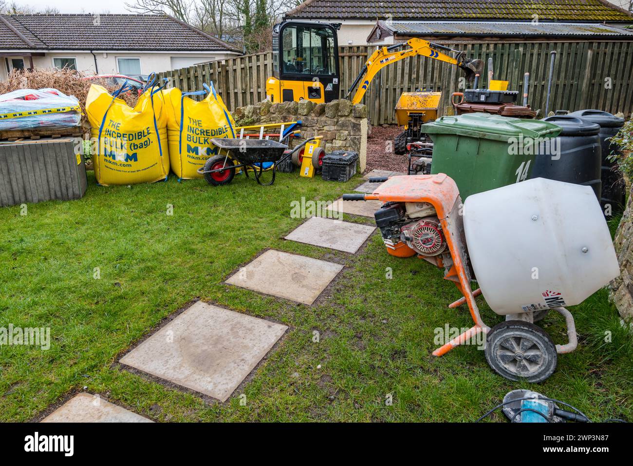 Machinery (small digger, dumper & cement mixer) for construction work in a driveway to build a garden room, Scotland, UK Stock Photo