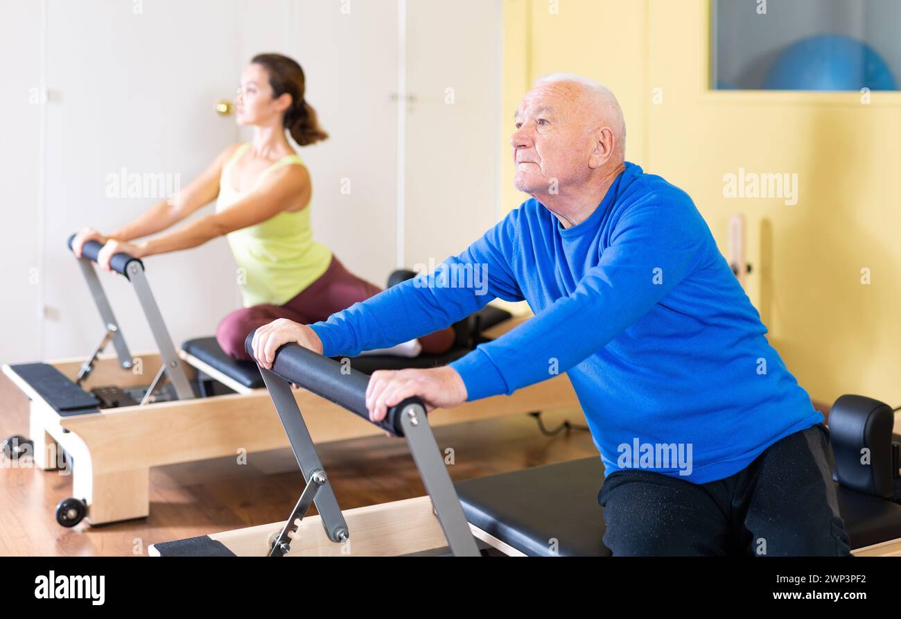 Senior man doing stretching exercises on pilates reformer Stock Photo ...