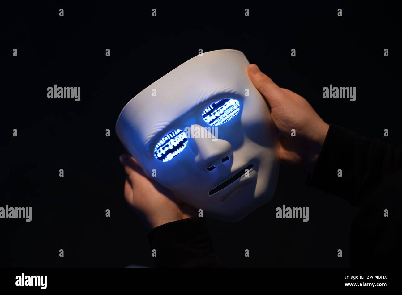 Hacker holding mask with programming code on dark background, closeup Stock Photo