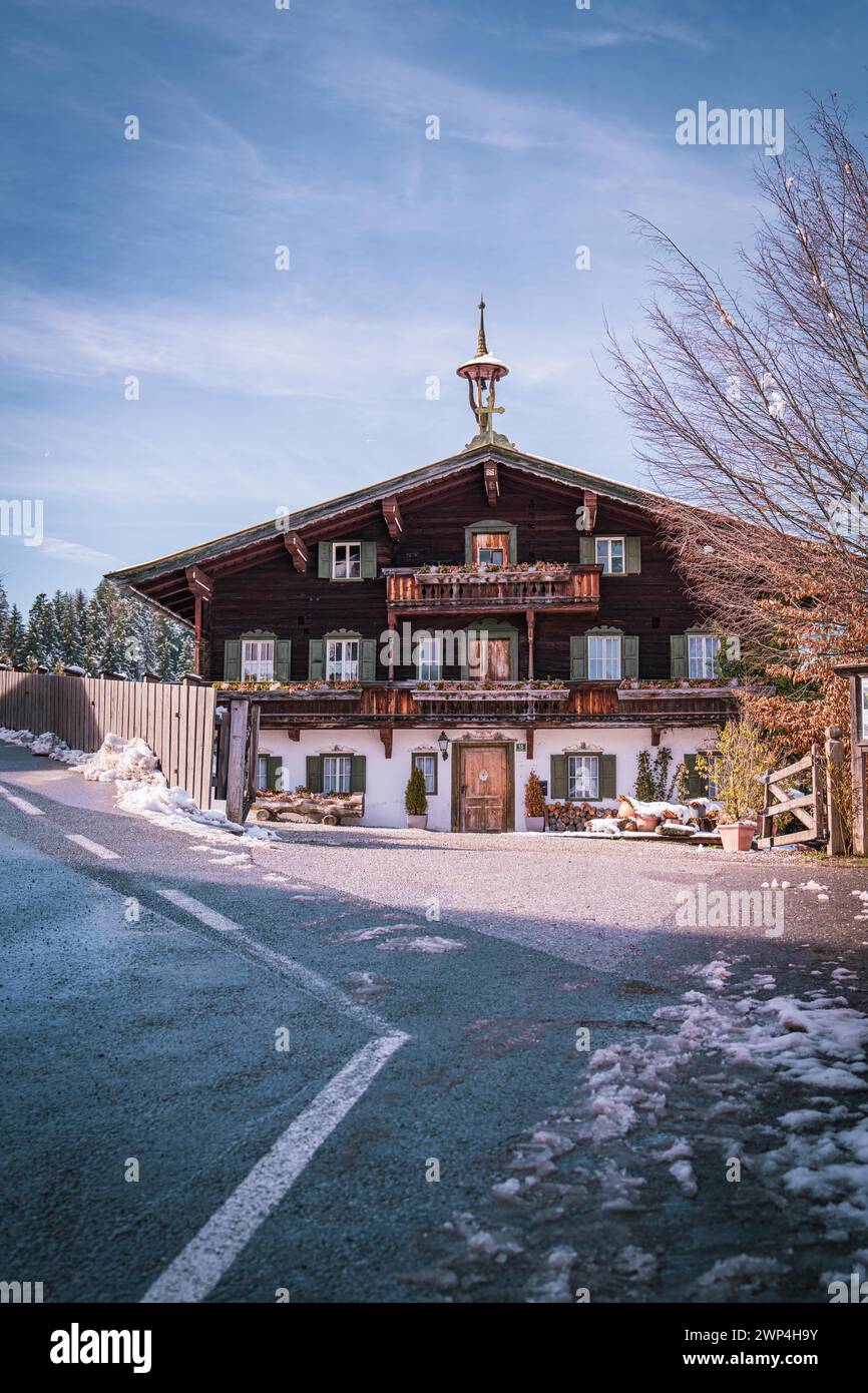 Traditional Bavarian country house on a snow-covered road under a clear blue sky, Der Bergdoktor practice, Elmau, Austria Stock Photo