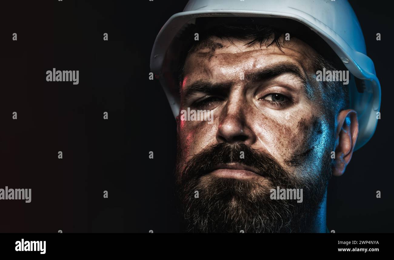 Closeup portrait of construction worker in hard hat. Pensive bearded man in protective helmet. Serious professional architect, contractor or male Stock Photo