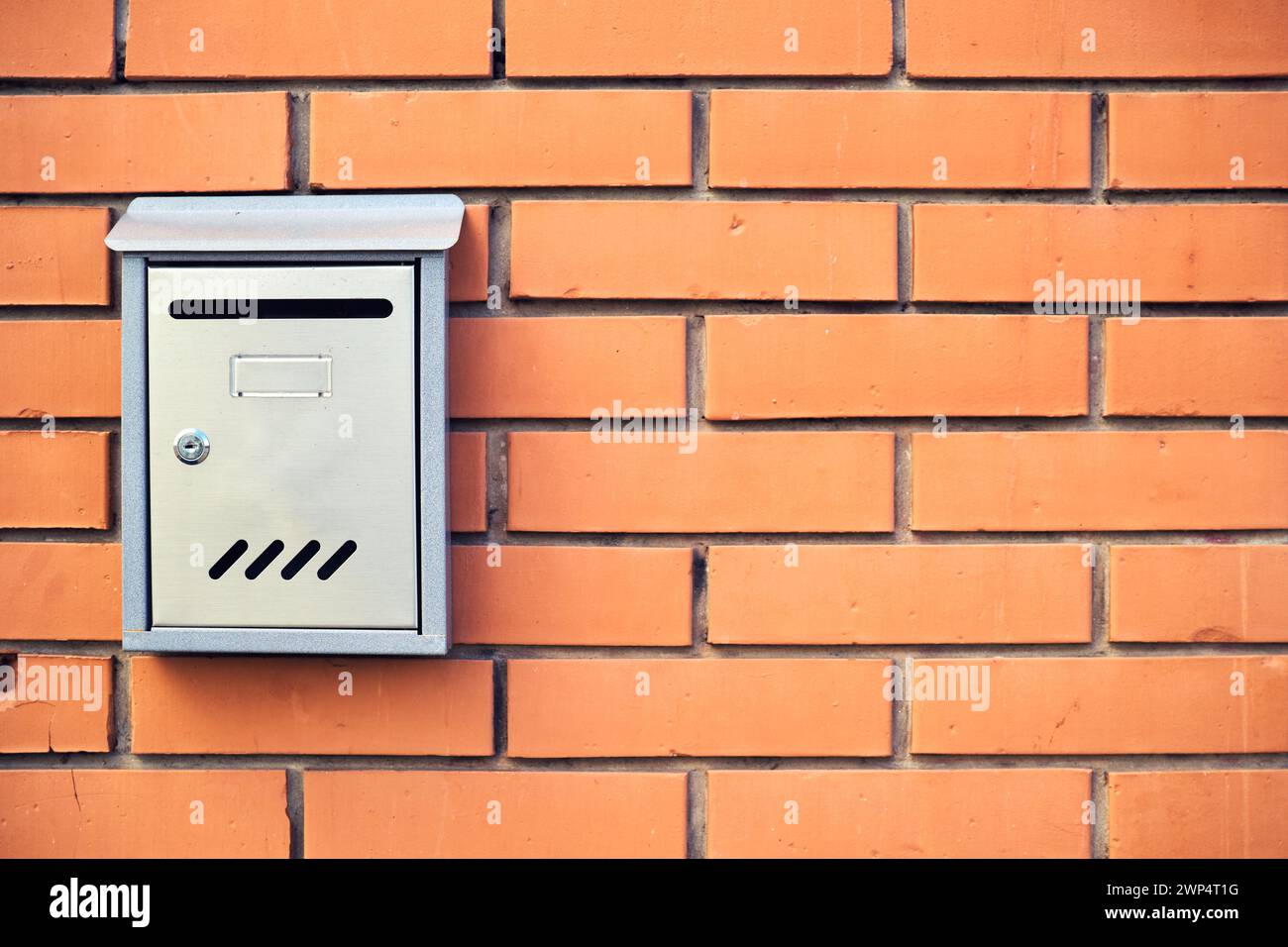 Metallic mailbox mounted on brick wall with copy space Stock Photo