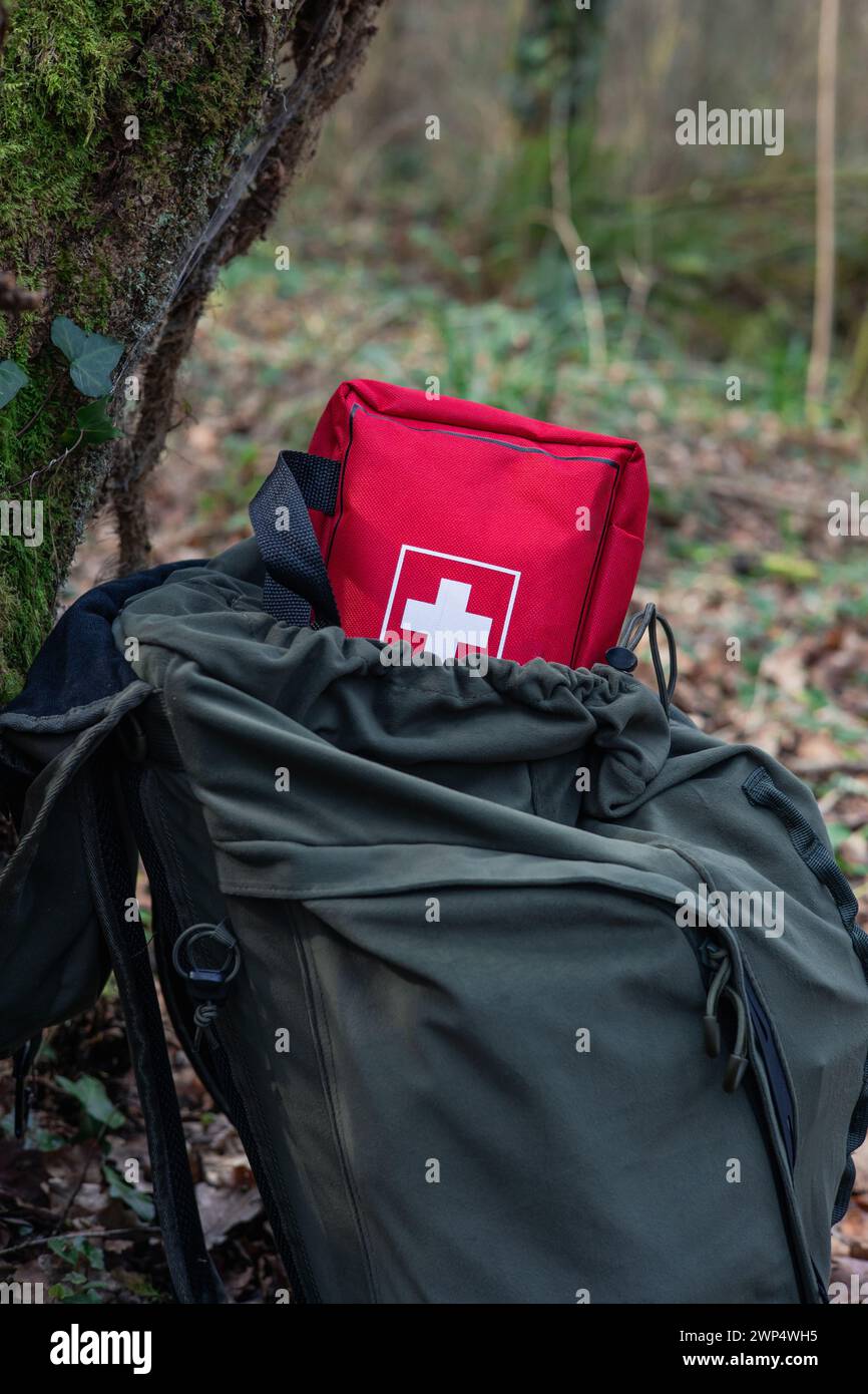 vertical portrait A survival backpack leans against a tree in the forest, revealing its first aid contents. This image encapsulates the essence of pre Stock Photo