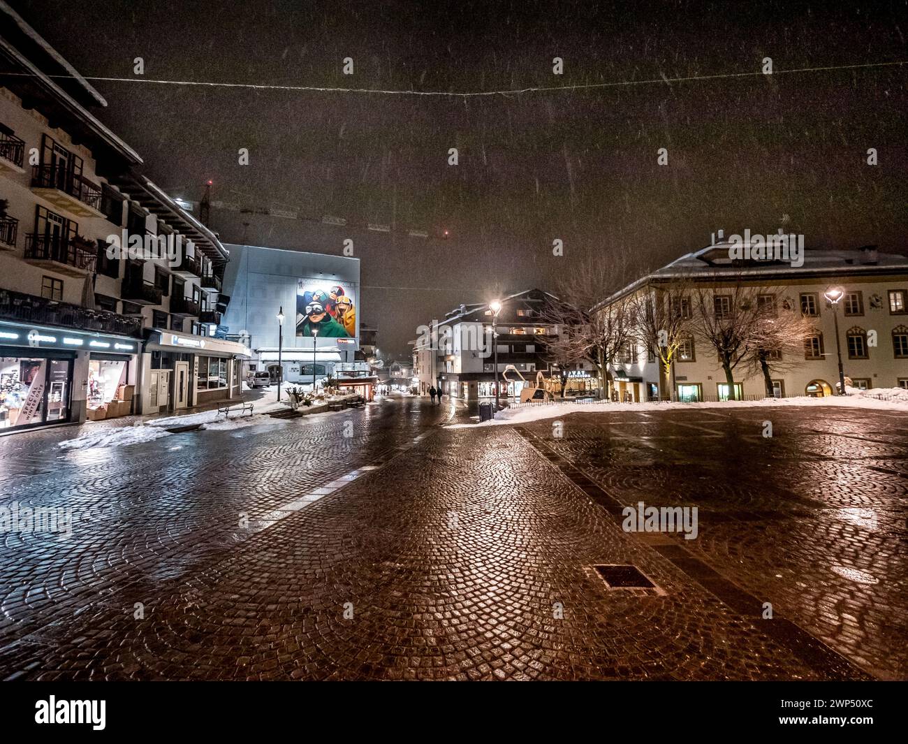 The image is of a winter night-time street scene in the resort town of Cortina d'Ampezzo located in the famous mountains of the Italian Dolomites Stock Photo