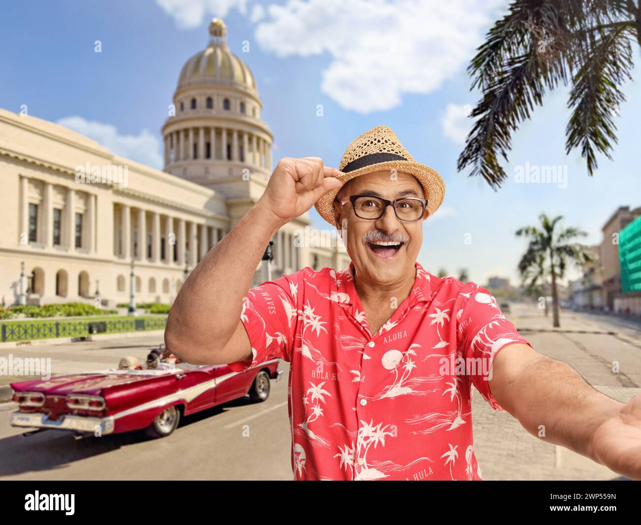 Happy mature tourist with a straw hat taking a selfie on the streets of Havana, Cuba Stock Photo